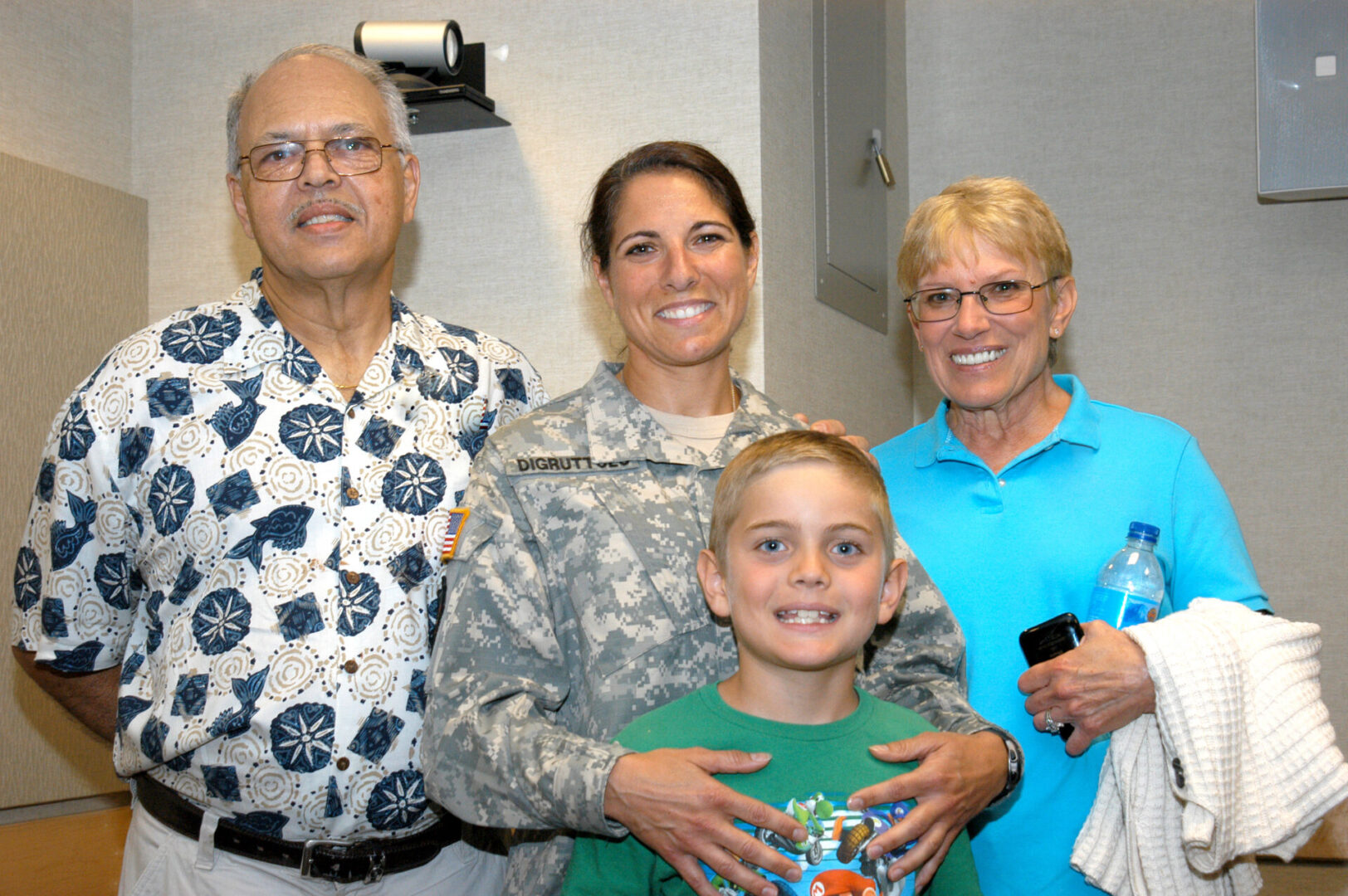 A family posing for the camera in front of a wall.